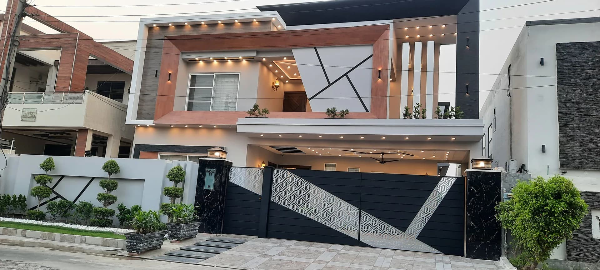 11 Indus — A modern evening-lit facade opening into marble halls, DC Colony, Gujranwala